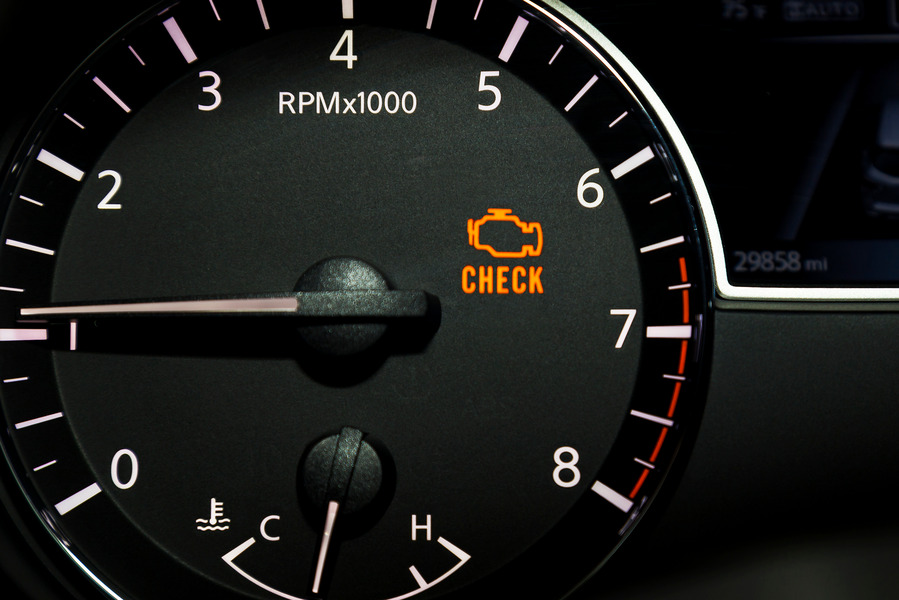 A close-up view of a car's tachometer showing the RPM dial and a warning light that says "CHECK" illuminated in orange.