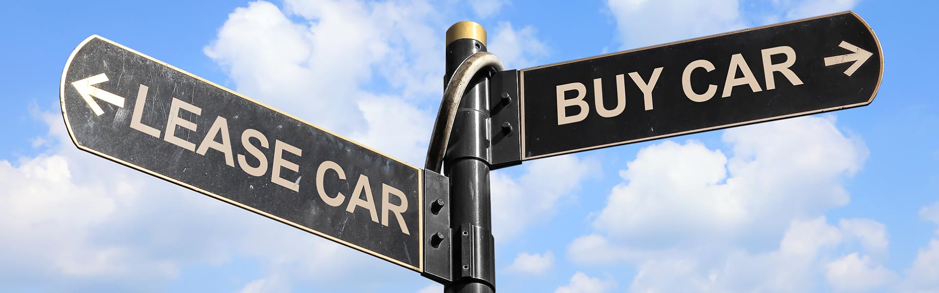 Signpost with two arrows pointing in opposite directions: one labeled "LEASE CAR" and the other "BUY CAR," against a blue sky with clouds.